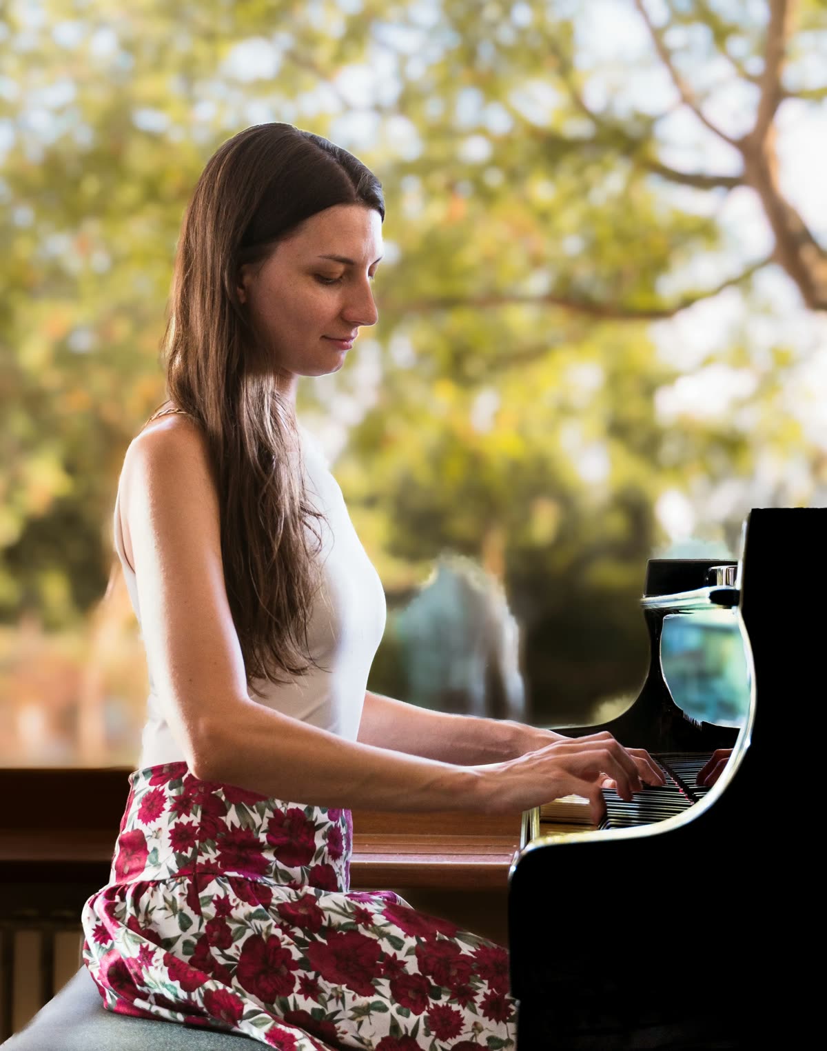 Mojca Pregeljc playing a grand piano by a sunlit window